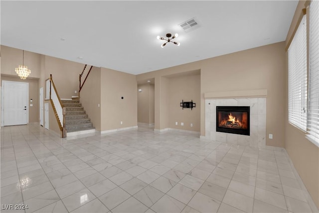 unfurnished living room with a tile fireplace and an inviting chandelier