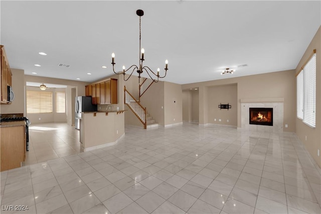 unfurnished living room with a fireplace, light tile patterned floors, a healthy amount of sunlight, and an inviting chandelier