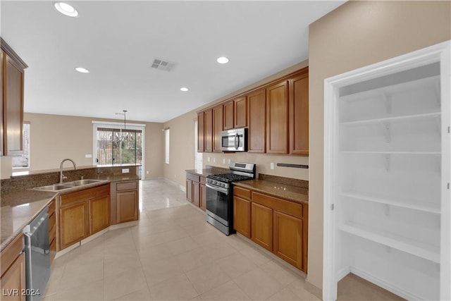 kitchen featuring sink, dark stone counters, a chandelier, pendant lighting, and appliances with stainless steel finishes