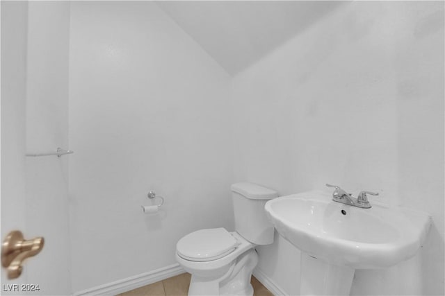 bathroom featuring tile patterned flooring, lofted ceiling, and toilet