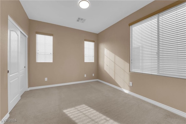 unfurnished bedroom featuring light carpet and a closet