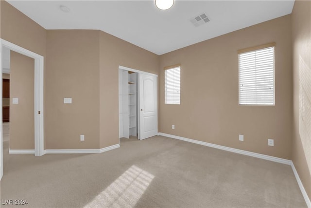 unfurnished bedroom featuring light carpet, a closet, and multiple windows