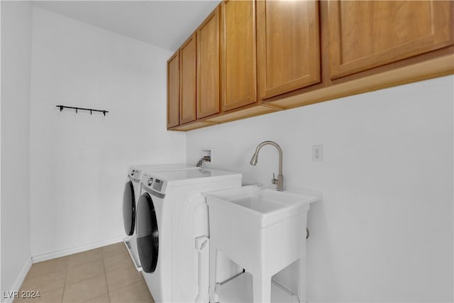 washroom featuring washing machine and clothes dryer, sink, light tile patterned flooring, and cabinets