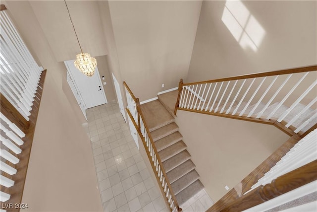 stairway with tile patterned flooring and a notable chandelier