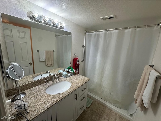 bathroom with tile patterned flooring, vanity, and a textured ceiling