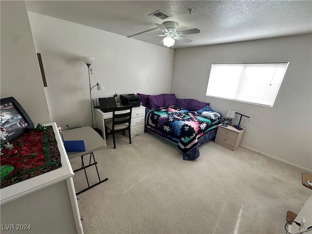 bedroom with ceiling fan, light colored carpet, and a textured ceiling