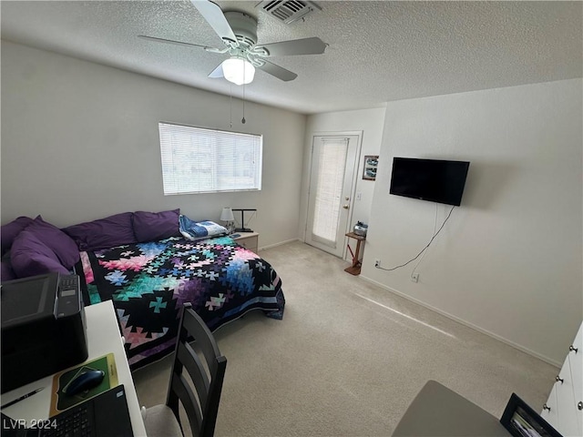 bedroom featuring ceiling fan, light colored carpet, and a textured ceiling