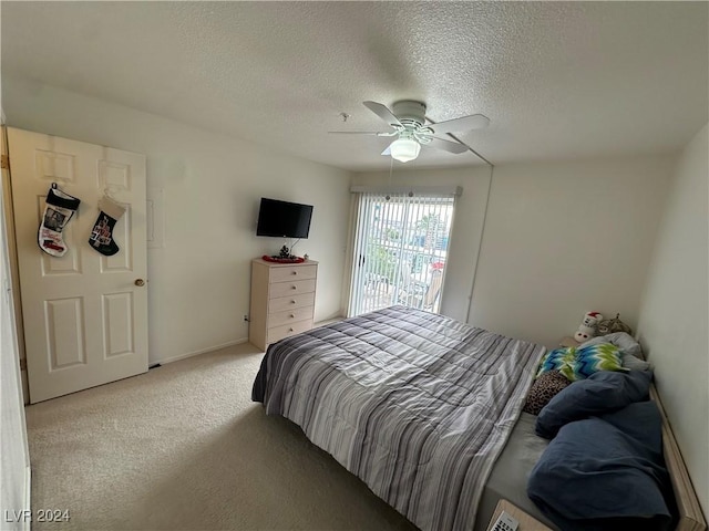 bedroom featuring ceiling fan, light colored carpet, and a textured ceiling