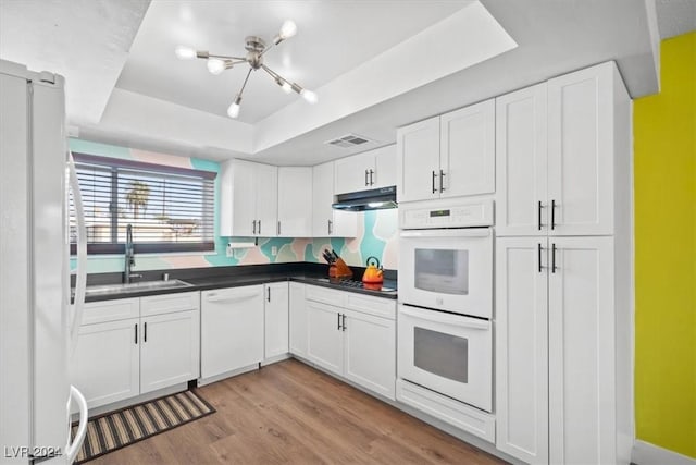 kitchen featuring white cabinets, white appliances, a raised ceiling, and sink