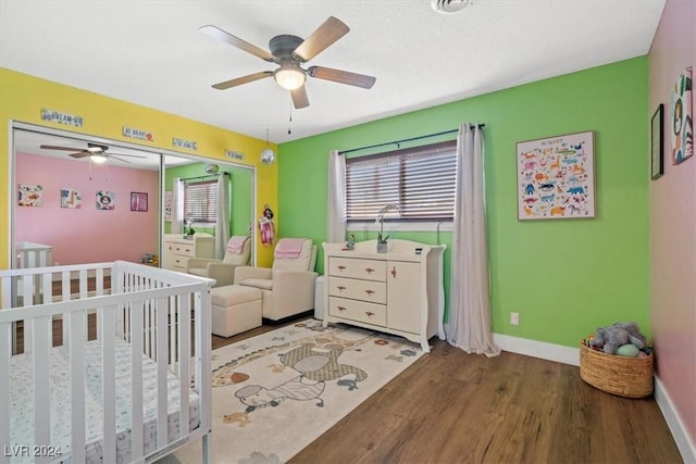 bedroom featuring hardwood / wood-style flooring, a nursery area, and ceiling fan