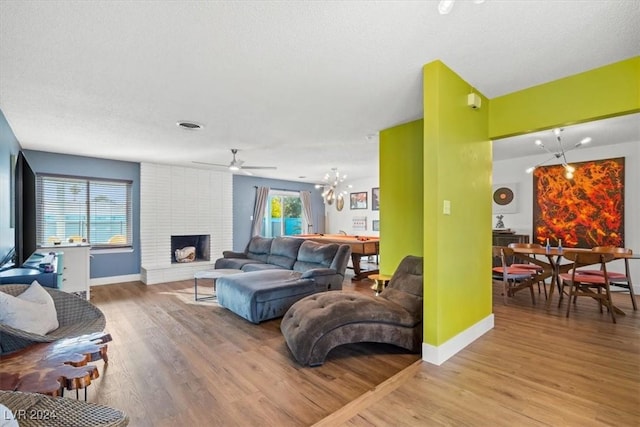 living room featuring a fireplace, ceiling fan, and light hardwood / wood-style flooring