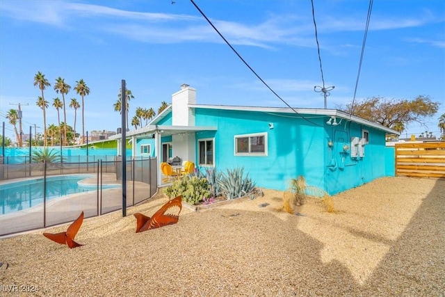 back of property with a fenced in pool