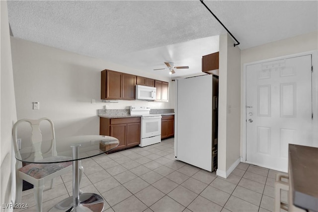 kitchen with a textured ceiling, ceiling fan, light tile patterned floors, and white appliances