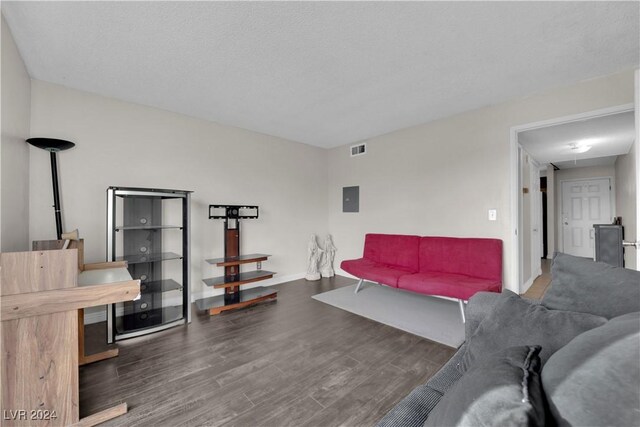 living room featuring dark hardwood / wood-style floors, a textured ceiling, and electric panel