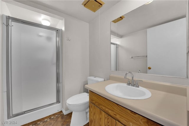 bathroom with tile patterned flooring, vanity, a shower with shower door, and toilet