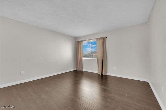 empty room with a textured ceiling and dark hardwood / wood-style floors