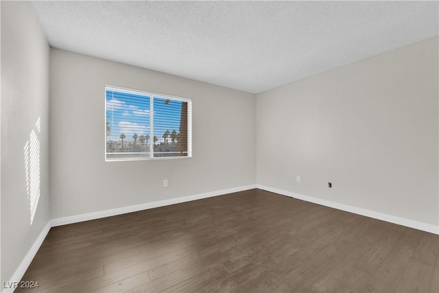 unfurnished room with a textured ceiling and dark hardwood / wood-style flooring