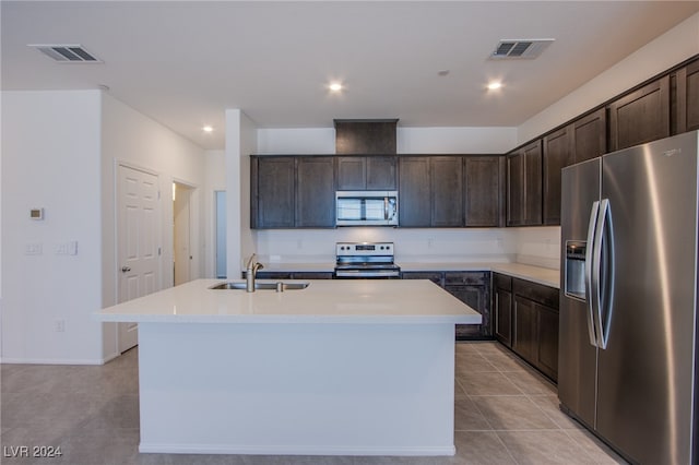 kitchen with appliances with stainless steel finishes, dark brown cabinetry, a center island with sink, and sink