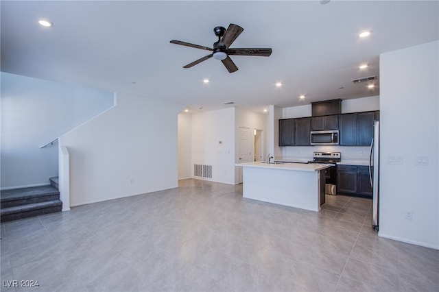 kitchen featuring a center island with sink, sink, ceiling fan, appliances with stainless steel finishes, and dark brown cabinetry