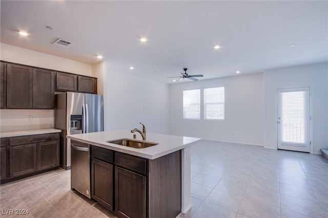 kitchen featuring appliances with stainless steel finishes, dark brown cabinetry, ceiling fan, sink, and a center island with sink