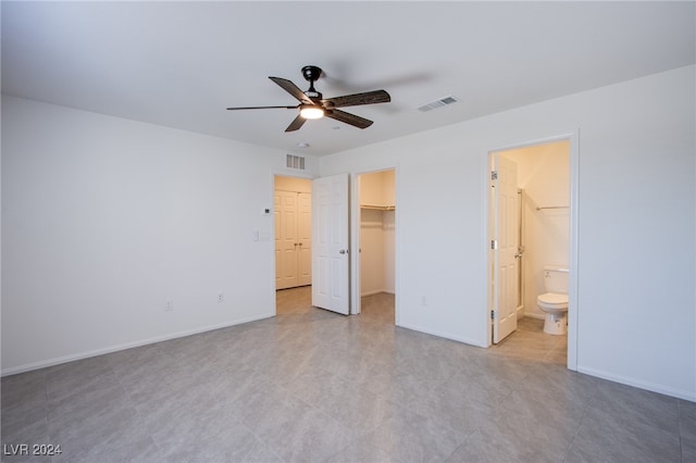 unfurnished bedroom featuring a closet, ensuite bathroom, a spacious closet, and ceiling fan