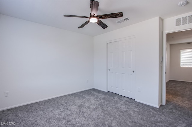 unfurnished bedroom featuring ceiling fan, dark carpet, and a closet