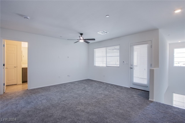 unfurnished room with dark colored carpet and ceiling fan