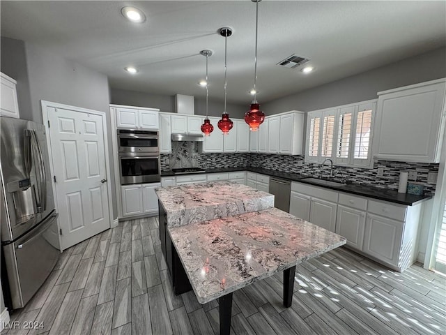 kitchen featuring pendant lighting, stainless steel appliances, white cabinetry, and sink