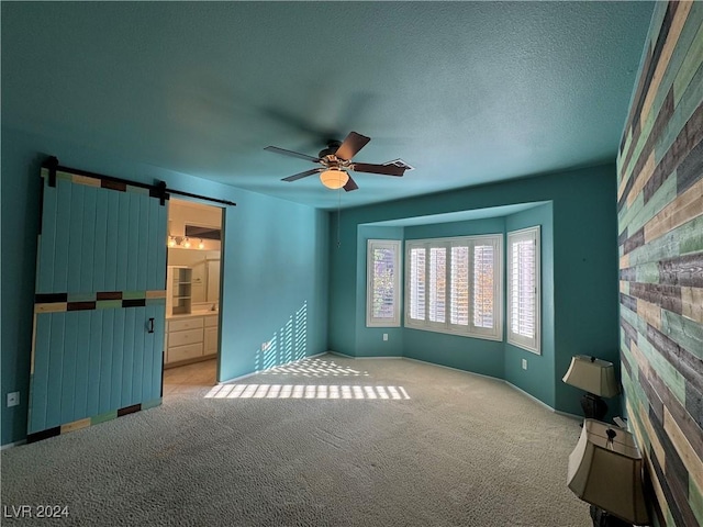 interior space featuring a textured ceiling, a barn door, and ceiling fan