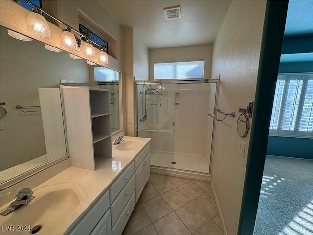 bathroom with tile patterned floors, vanity, a textured ceiling, and walk in shower