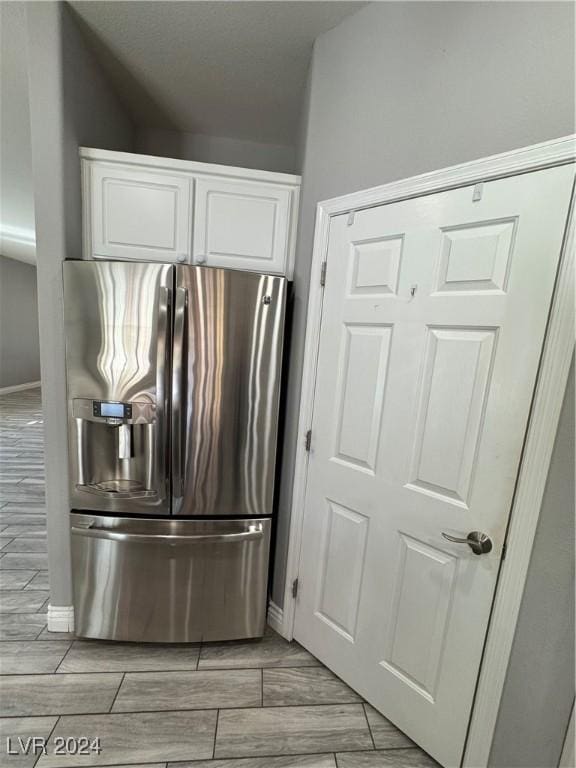 kitchen with white cabinetry and stainless steel refrigerator with ice dispenser