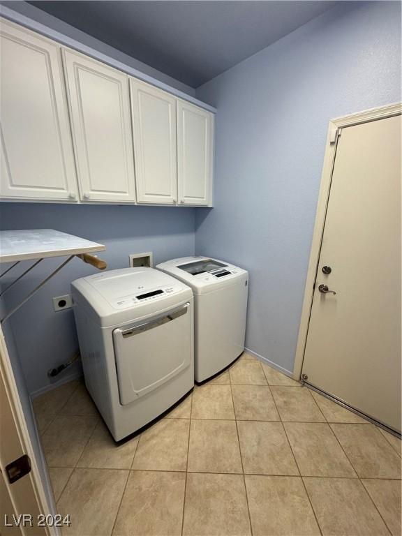 clothes washing area with cabinets, washer and clothes dryer, and light tile patterned flooring