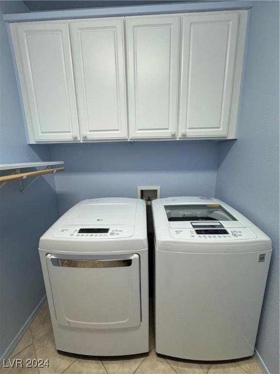 laundry room featuring cabinets, washing machine and dryer, and light tile patterned floors