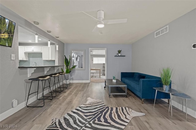 living room featuring ceiling fan, light hardwood / wood-style flooring, and sink