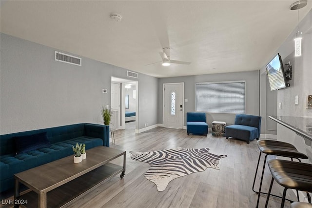 living room featuring light wood-type flooring, ceiling fan, and a healthy amount of sunlight