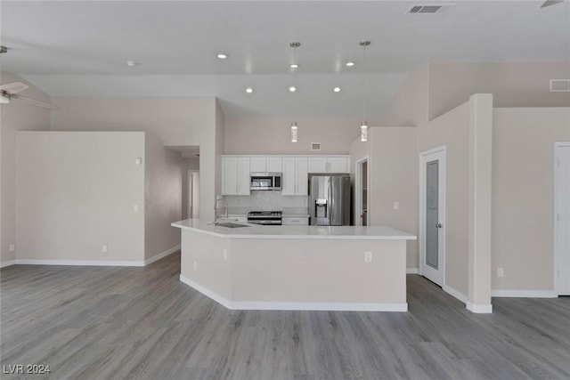 kitchen featuring white cabinets, a large island with sink, stainless steel appliances, and decorative light fixtures