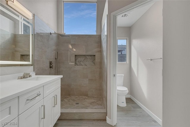 bathroom featuring tiled shower, hardwood / wood-style floors, vanity, and toilet