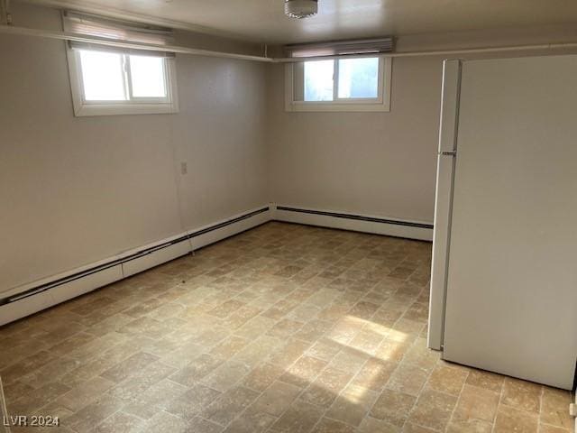 basement with baseboard heating and white fridge