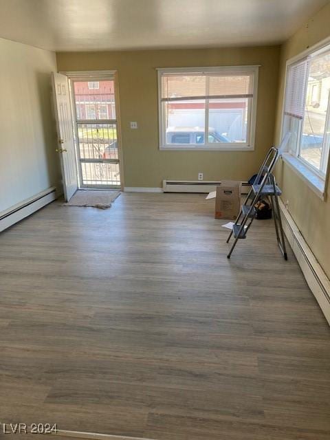 empty room featuring hardwood / wood-style floors and a baseboard heating unit