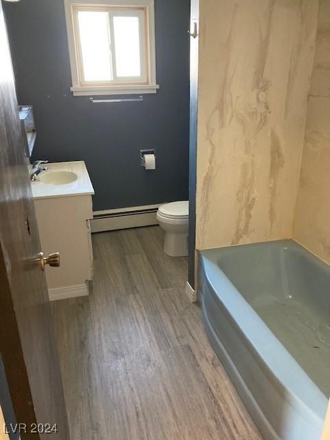 bathroom with vanity, a baseboard heating unit, wood-type flooring, toilet, and a tub