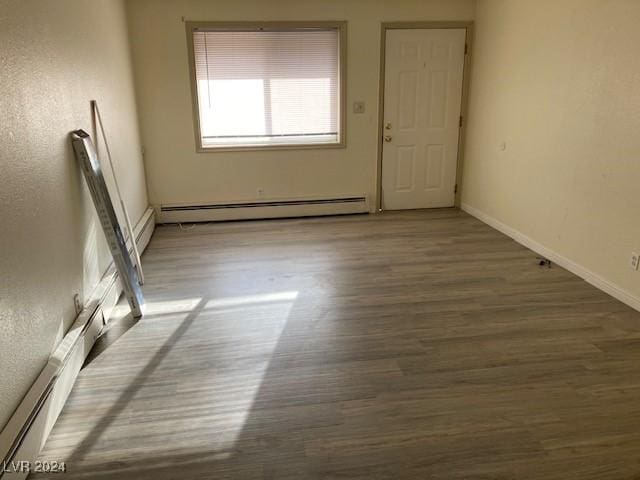 unfurnished room featuring dark hardwood / wood-style flooring and a baseboard radiator