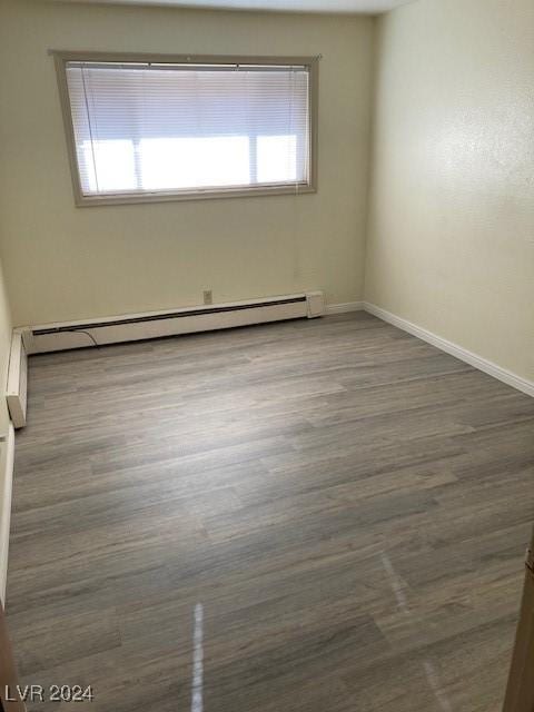 empty room featuring baseboard heating and dark wood-type flooring