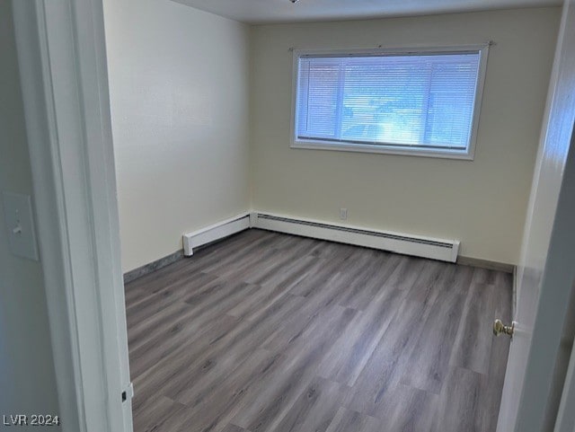 empty room featuring a baseboard radiator and light hardwood / wood-style floors