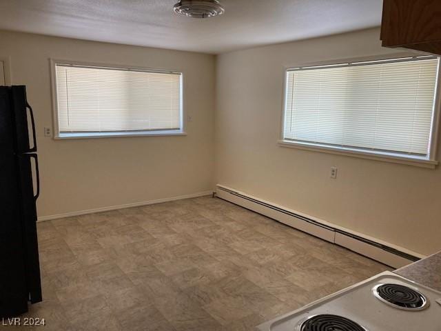 interior space with black refrigerator and a baseboard heating unit