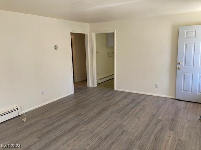 empty room featuring dark hardwood / wood-style floors and a baseboard heating unit