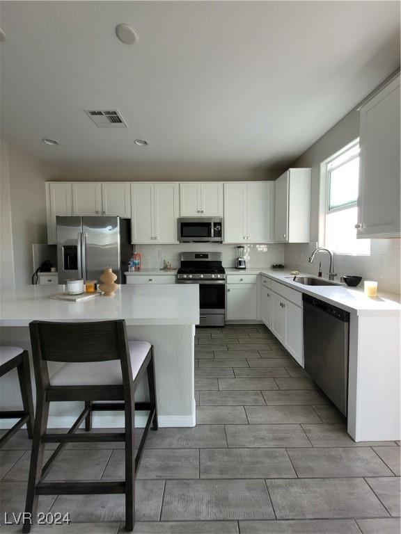 kitchen featuring white cabinets, appliances with stainless steel finishes, a breakfast bar, and sink