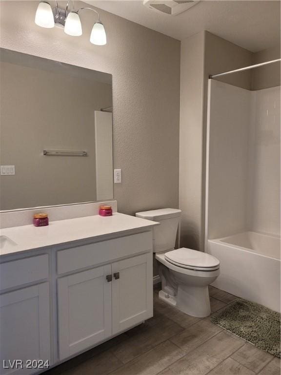bathroom with vanity, a textured wall, wood finished floors, toilet, and washtub / shower combination