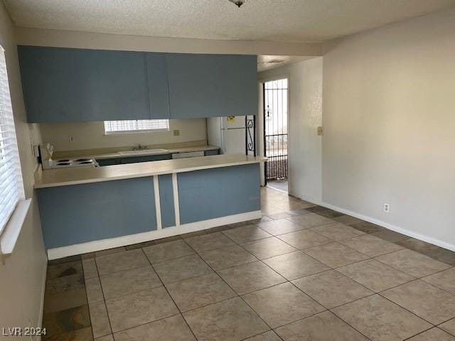 kitchen featuring a textured ceiling, white fridge, stove, and sink