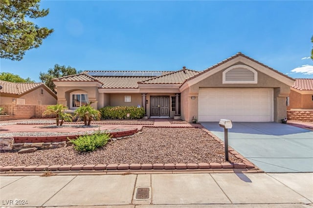 8705 Villa Ridge Dr, Las Vegas, NV 89134 - view of front of house with stucco siding, an attached garage, concrete driveway, roof mounted solar panels, and a tile roof