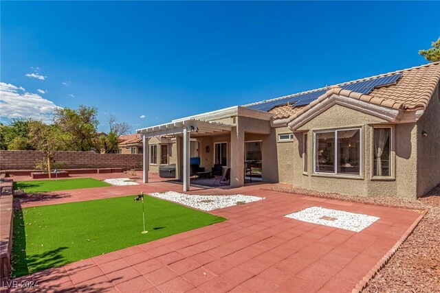 8705 Villa Ridge Dr, Las Vegas, NV 89134 - back of house with an area to practice putting, a pergola, stucco siding, a patio area, and roof mounted solar panels